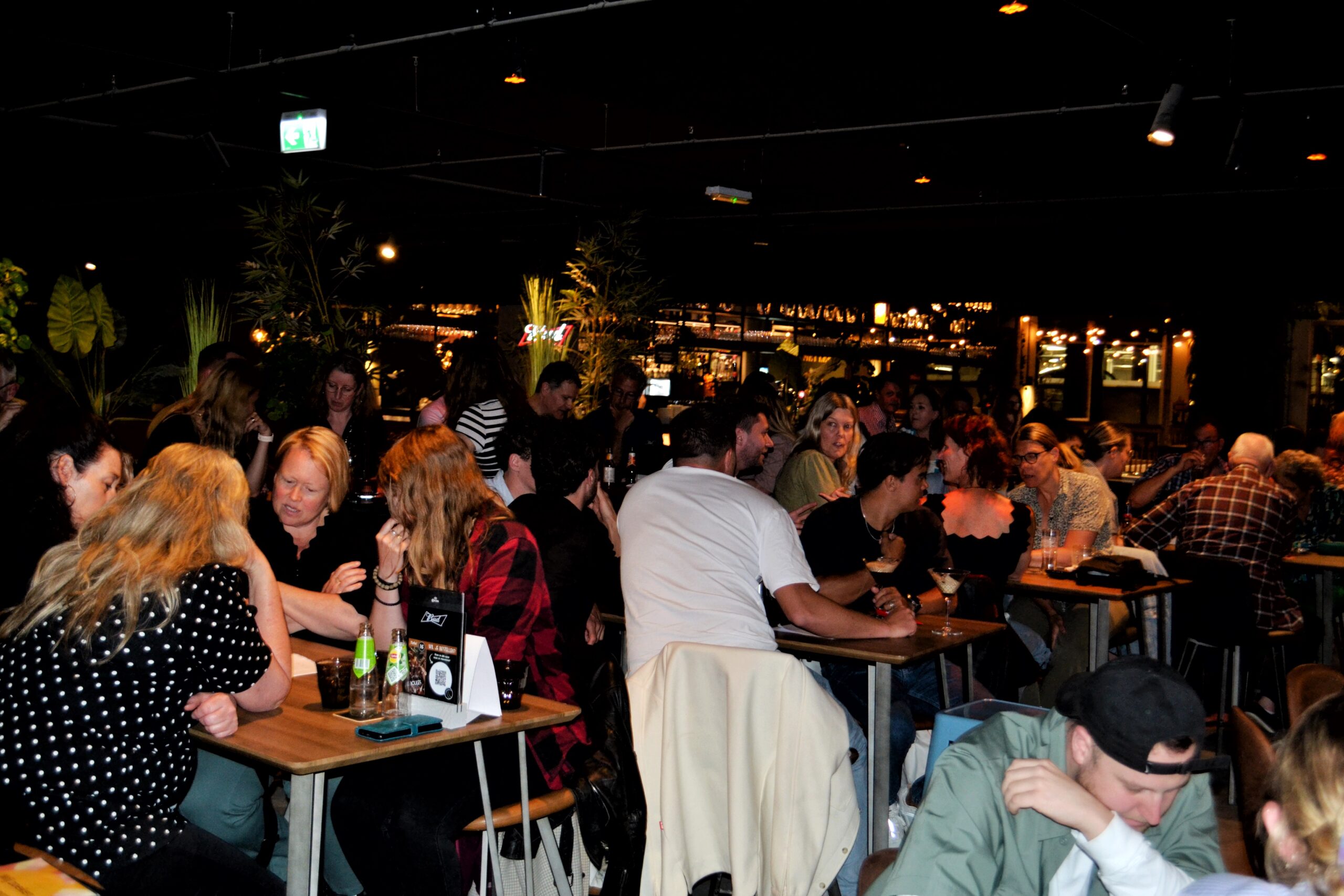 Groep mensen zittend aan tafels in een cafe